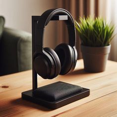 headphones are sitting on top of a wooden table next to a potted plant