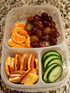 a plastic container filled with different types of fruits and veggies on top of a counter