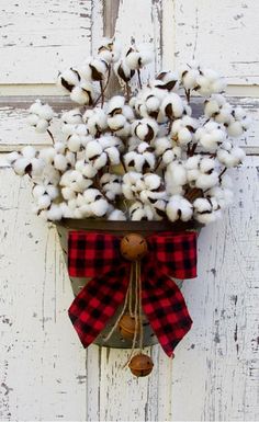 a bunch of cotton in a bucket hanging on a door with a red and black bow