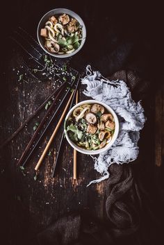 two bowls filled with food next to chopsticks on top of a wooden table