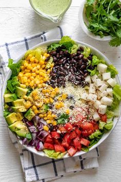 a salad with black beans, tomatoes, avocado, corn and lettuce