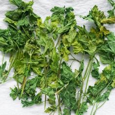 some green leafy plants are laying on a white surface and ready to be used as garnishes