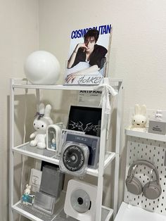 there is a shelf with various items on it in the bathroom, along with a magazine and headphones