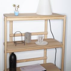 a wooden shelf with a lamp on top and other items sitting on the shelves next to it