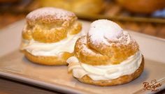 two pastries sitting on top of a plate covered in powdered sugar and icing