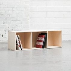 a book shelf with two books on it and a brick wall in the back ground