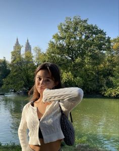 a beautiful young woman standing next to a lake