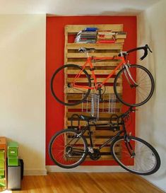 a bicycle mounted to a wooden pallet in front of a red wall with bookshelves