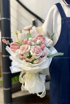 a bouquet of flowers sitting on top of a wooden table next to a person in overalls