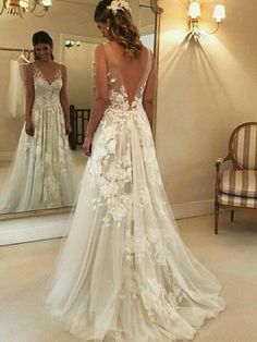 a woman standing in front of a mirror wearing a wedding dress with flowers on it