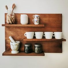 there are cups and spoons on the shelf