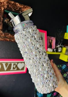 a person holding a water bottle with pearls on it