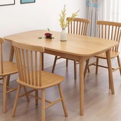 a dining room table with four chairs and a vase on the top of it in front of a window