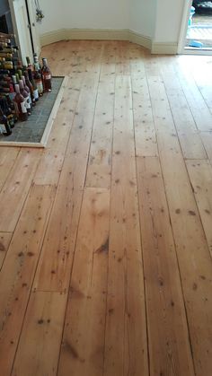 an empty room with wood floors and bottles on the floor