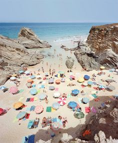 people are on the beach with umbrellas in the sand and cliffs to the side