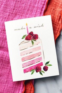 a piece of cake on top of a pink towel next to a card that says make a wish