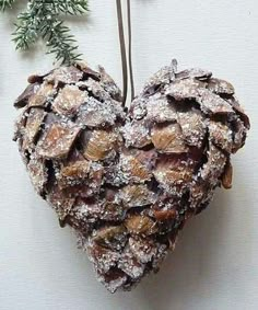 a pine cone shaped ornament hanging from a tree branch with snow on it