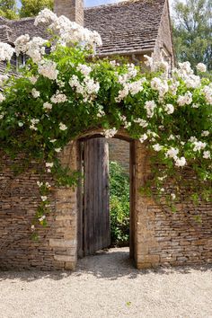 an old brick building with white flowers growing on it's sides and doors open