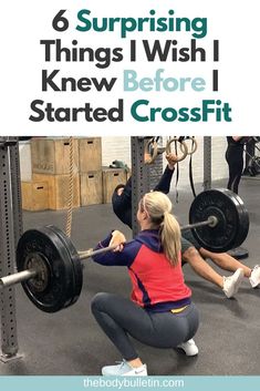 a woman squats on the ground while holding a barbell in front of her