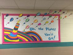 a bulletin board hanging on the wall in a school hallway with balloons floating above it