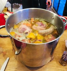 a large metal pot filled with food on top of a wooden table