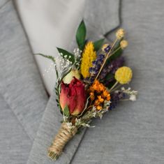 a boutonniere with flowers and greenery on the lapel of a man