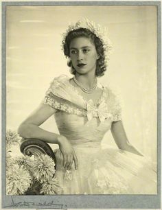 an old black and white photo of a woman in a dress with flowers on her head