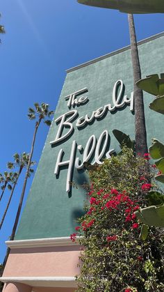 the beverly hotel sign and palm trees against a blue sky