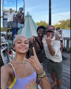 two men and a woman standing on a dock posing for the camera with their fingers in the air