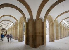 people are walking through an arched hallway with stone arches on the walls and flooring