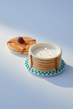 two plates with donuts on them, one has a candle and the other is a bowl