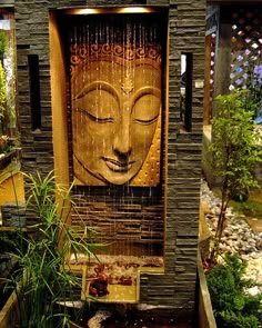 a water fountain with a buddha face on the side and plants growing in pots next to it