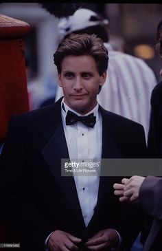 a man in a tuxedo and bow tie is standing next to another person