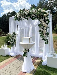 an outdoor ceremony setup with white flowers and greenery