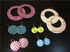 six pairs of earrings are shown on a black surface with white and pink polka dots