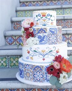 a multi - tiered wedding cake with flowers on the top is sitting on some steps