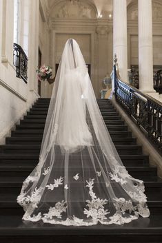 the bride is walking down the stairs in her wedding dress with a veil over her head