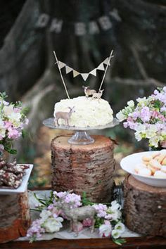 a table topped with cake and desserts covered in frosted icing next to trees