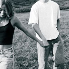 a man and woman holding hands in a field