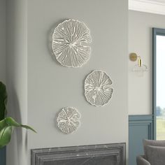 three white wall hangings on the side of a fireplace