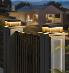 two lights that are on the side of a fence in front of a house at night