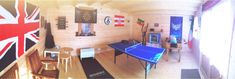 a room with a ping pong table in the center and an union jack flag on the wall