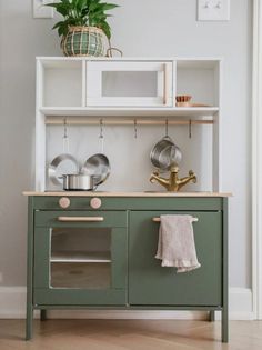 a green kitchen island with pots and pans on it, next to a potted plant