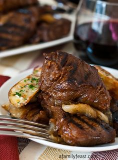 a plate topped with steak and french fries next to a glass of wine