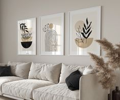 three framed art prints hang on the wall above a white couch in a living room