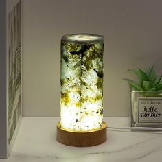 a glass jar with rocks inside sitting on a table next to a potted plant