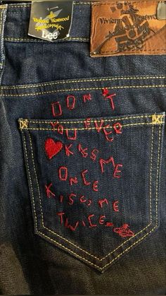 the back pocket of a pair of jeans with embroidered words on them and hearts in red ink