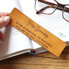 a person holding an open book with glasses on it