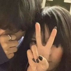 a man and woman making the v sign with their fingers in front of each other