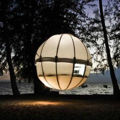 a large white ball sitting on top of a sandy beach next to the ocean at night